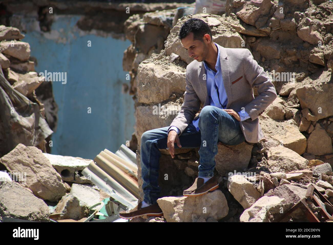 Taiz / Yémen - 13 avril 2017 : UN homme yéménite assis devant une maison détruite dans la guerre à Taiz, Yémen. Banque D'Images