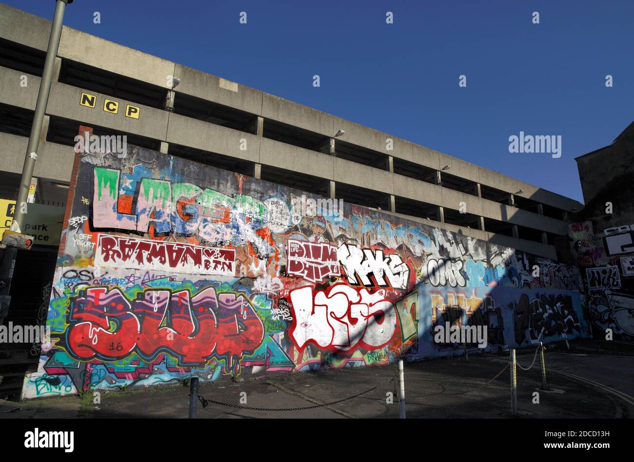 Graffitis sur un mur à côté d'un parking NCP à plusieurs étages près du centre-ville de Brighton. Banque D'Images