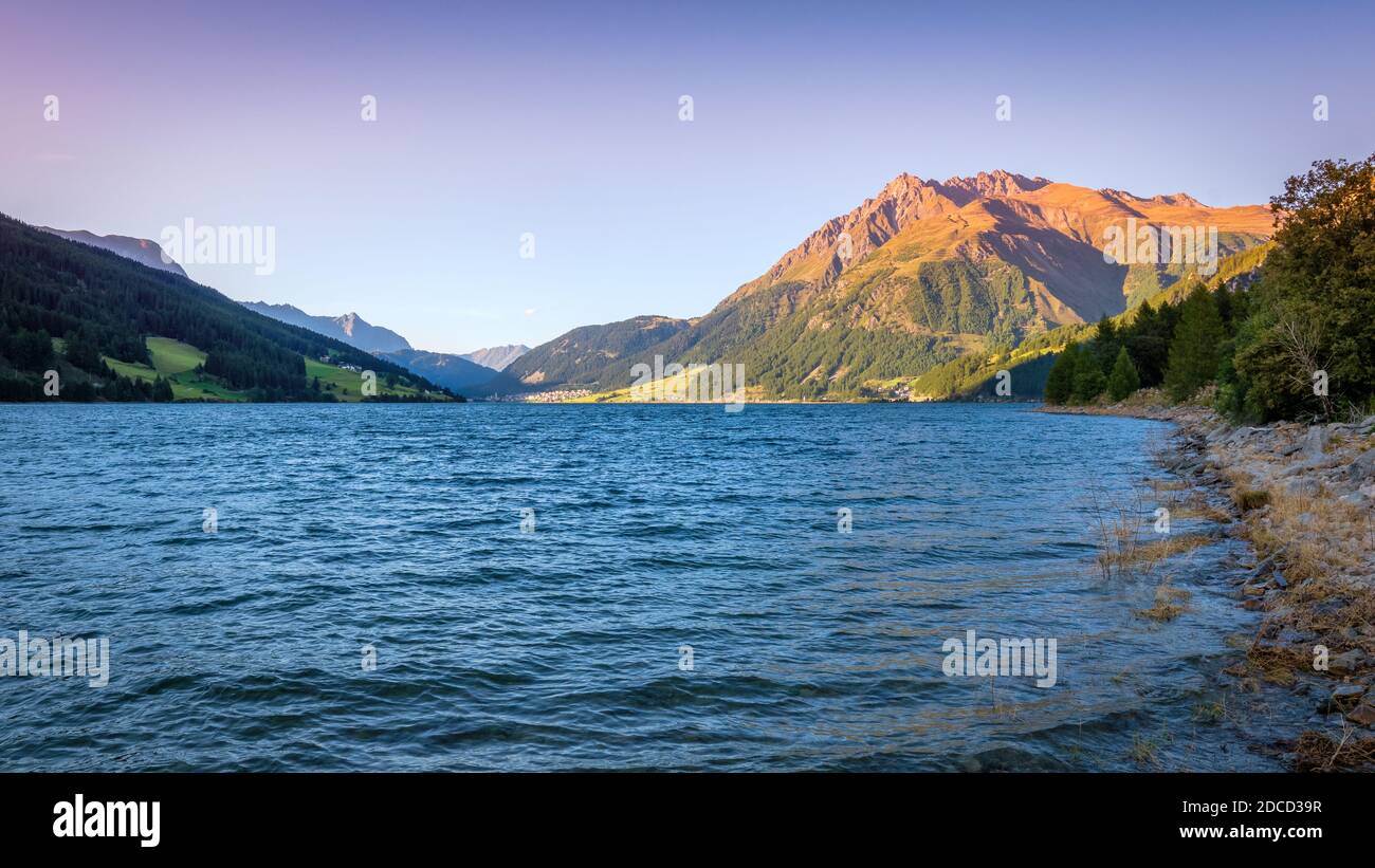 Coucher de soleil sur le lac Resia (allemand: Reschensee) et le village Resia à Val Venosta (Alto Adige, Italie). Il se trouve à côté du lac della Muta, en allemand: Haidersee Banque D'Images