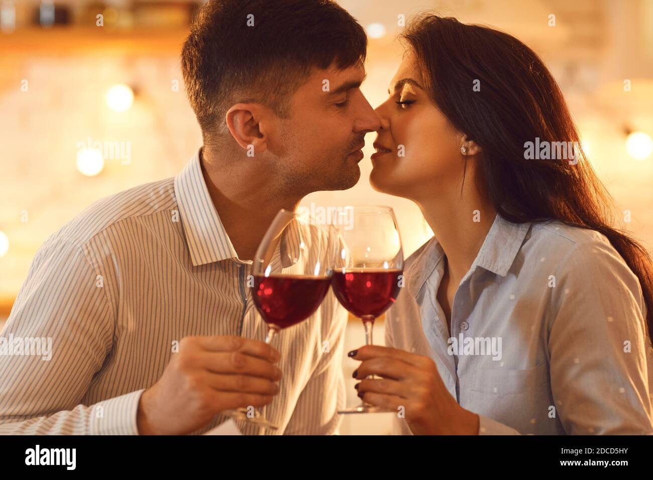 Jeune couple aimant s'embrassant et tenant des verres de Vin pendant la fête de la Saint-Valentin Banque D'Images