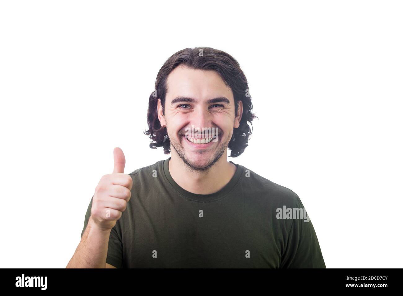 Jeune homme content, montre le pouce vers le haut geste, souriant à l'appareil photo, isolé sur fond blanc. Joli gars décontracté, long style curly cheveux, joyeux emot Banque D'Images