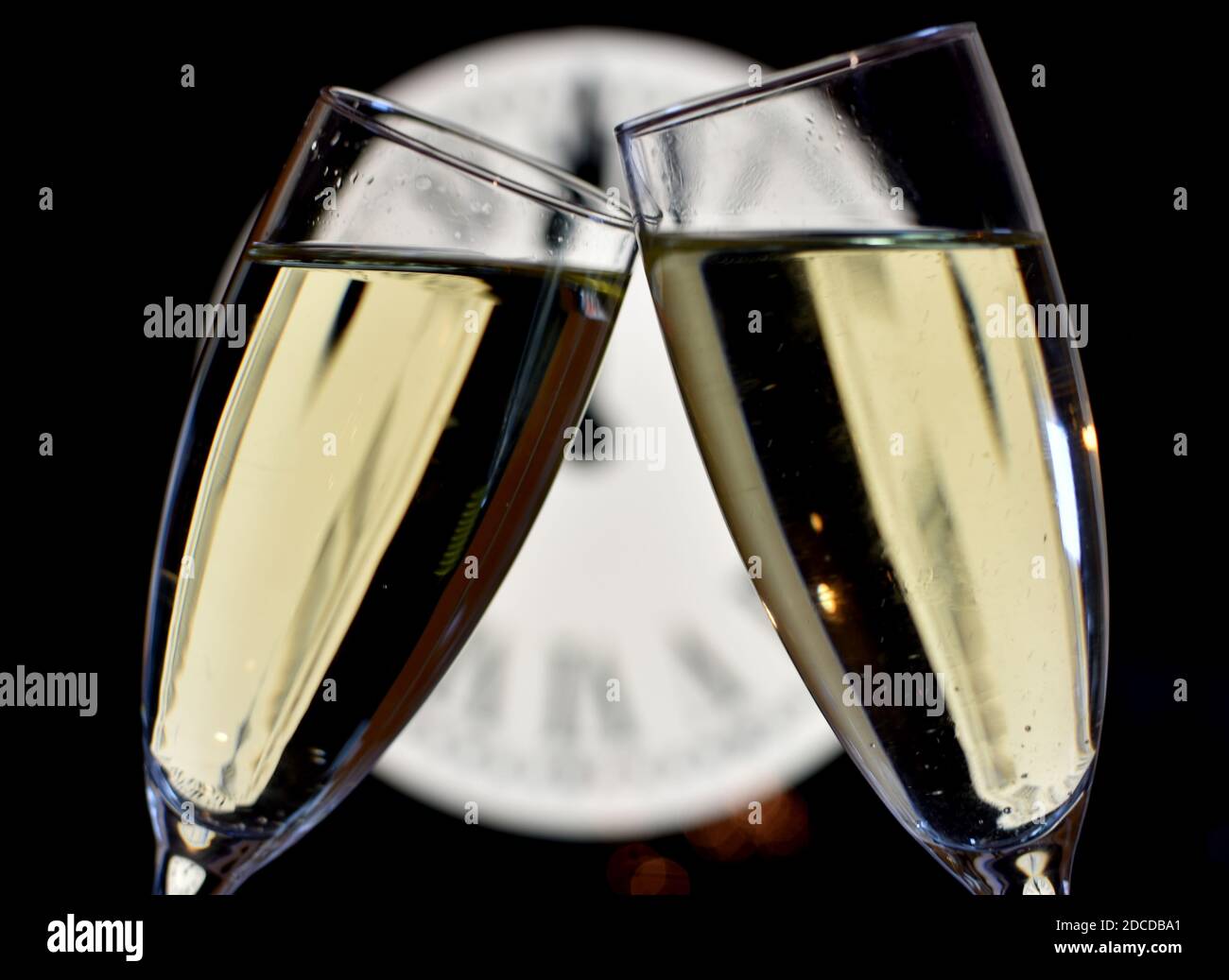 CÉLÉBRATION DE LA NOUVELLE ANNÉE, des verres levant avec du champagne avec l'horloge non focalisée Banque D'Images