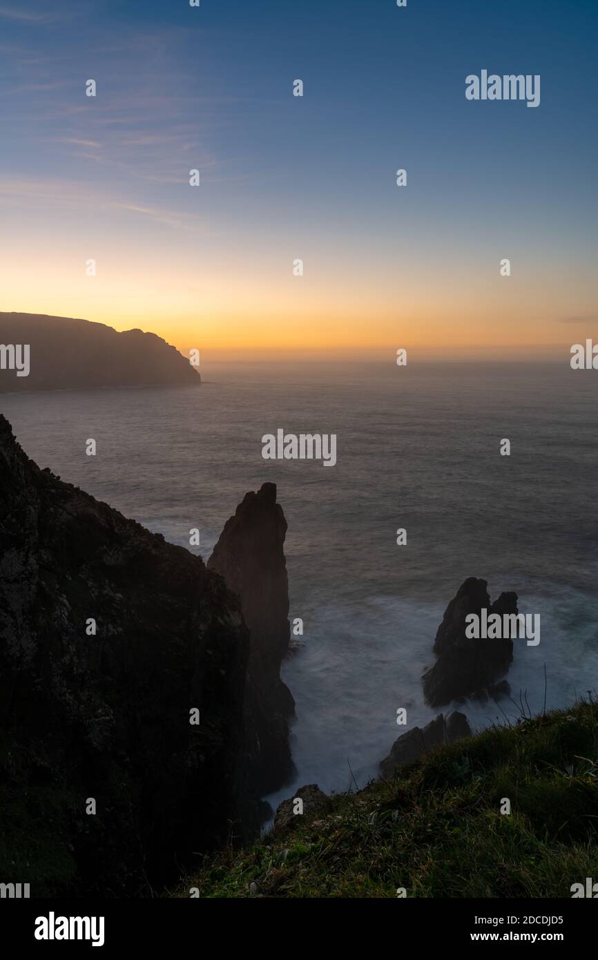 Un lever de soleil sur l'océan avec une falaise en silhouette et des couleurs magnifiques Banque D'Images