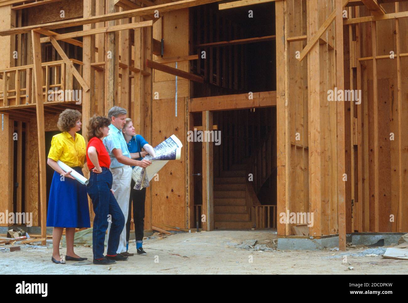 La famille de quatre examine les plans pour leur nouvelle maison en construction, 1991, CA, USA Banque D'Images