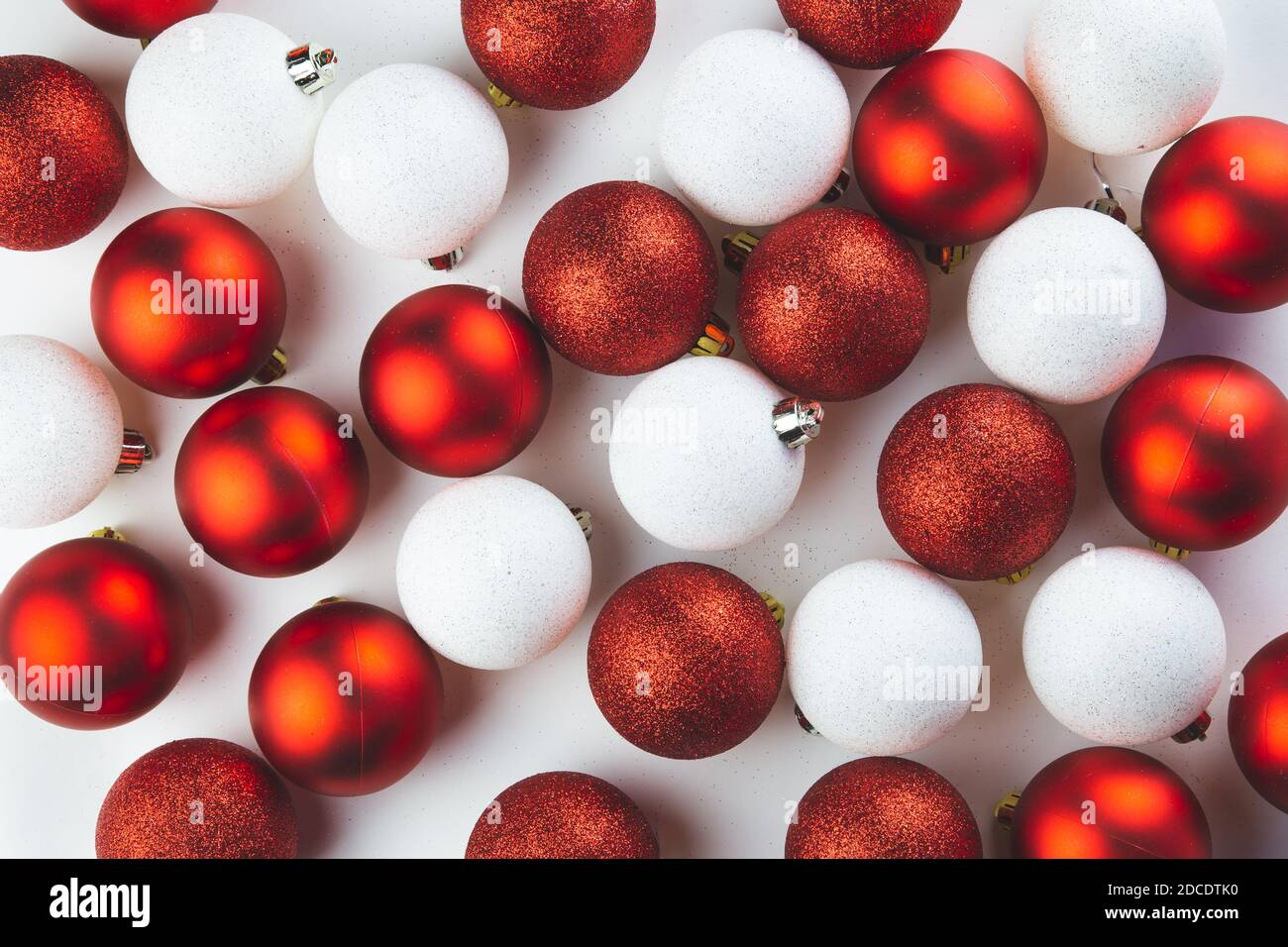 Des boules rouges et blanches de décorations d'arbre de Noël sont dispersées sur une table blanche. Noël, fond du nouvel an, carte postale. Banque D'Images