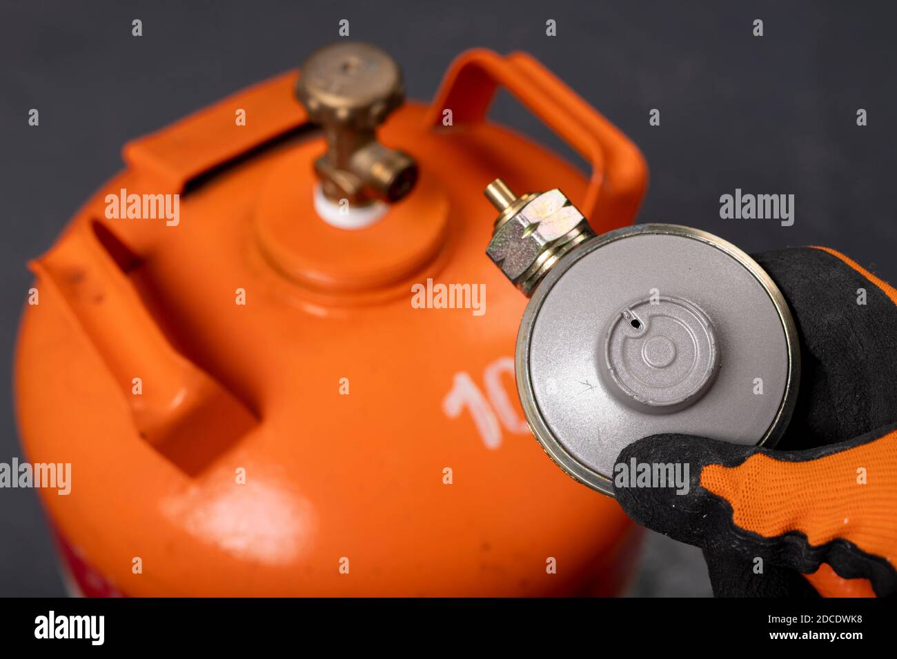 Bouteille de gaz propane-butane et réducteur. Gaz combustible utilisé dans les ménages. Arrière-plan sombre. Banque D'Images