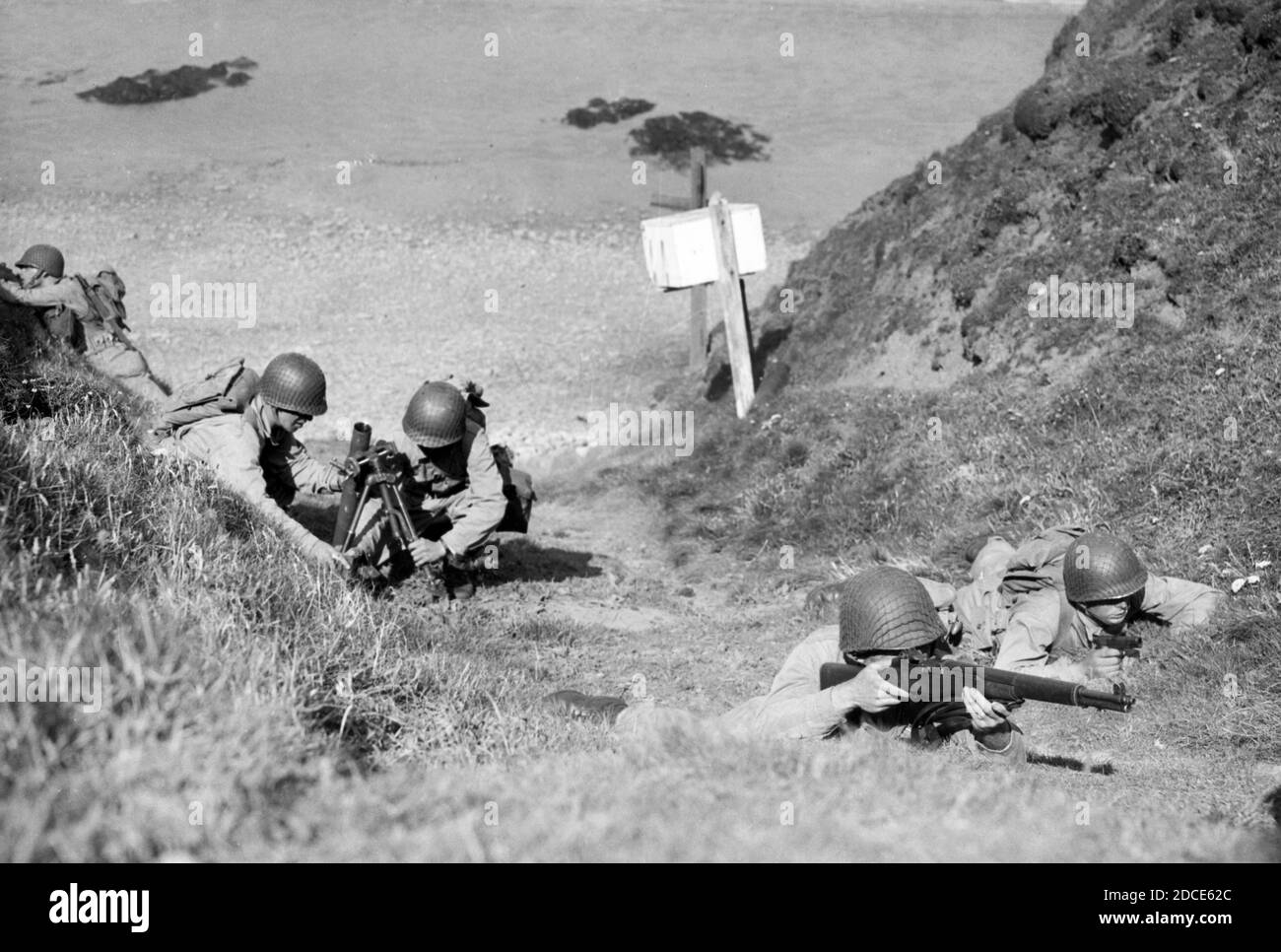 WW II - troupes de l'armée américaine lors d'un atterrissage sur la plage, à Bude, sur une côte ouest de l'Angleterre. Alors que trois hommes du 29e Bataillon des Rangers, avec des carbines, un pistolet et des sacs à dos assurent la couverture, deux autres hommes sont en cours de mise en place d'un mortier de 60 mm. Il s'agit d'une manœuvre de formation réaliste, en préparation à l'invasion européenne pleine d'espoir. Pour voir mes autres images WW II, Sea+rch: Prestor vintage WW II Banque D'Images