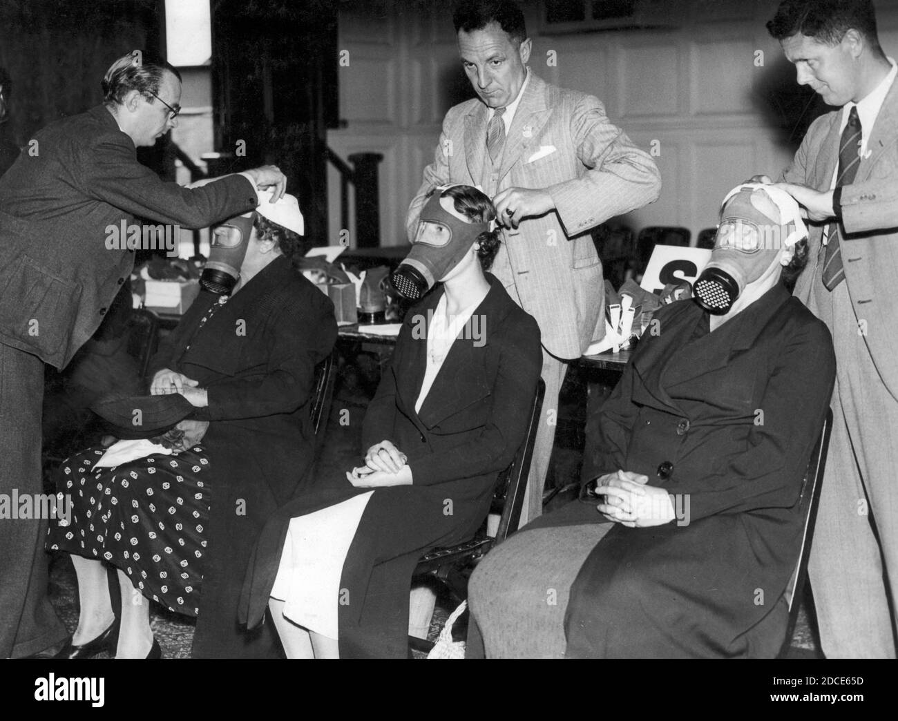 En 1939, trois femmes civiles sont installées pour leur propre masque à gaz personnel. L'Allemagne commençait à mener des actions de type guerre contre ses voisins. Vingt ans plus tôt, la première Guerre mondiale avait montré les horreurs du gaz toxique utilisé comme arme, et en Espagne des années 1930, des civils avaient subi des attaques au gaz par des avions. La Grande-Bretagne a compris qu'une attaque similaire de l'Allemagne serait dévastatrice pour sa population. À la fin de 1939, chaque homme, chaque femme et chaque enfant de Grande-Bretagne se faisait délivrer un masque à gaz. Pour voir mes autres images WW II, recherchez: Prestor vintage WW II Banque D'Images