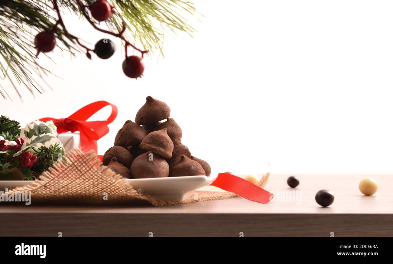 Pièce maîtresse décorative de Noël sur base en bois avec assiette pleine de truffes au chocolat avec fond blanc isolé. Vue avant. Position horizontale Banque D'Images