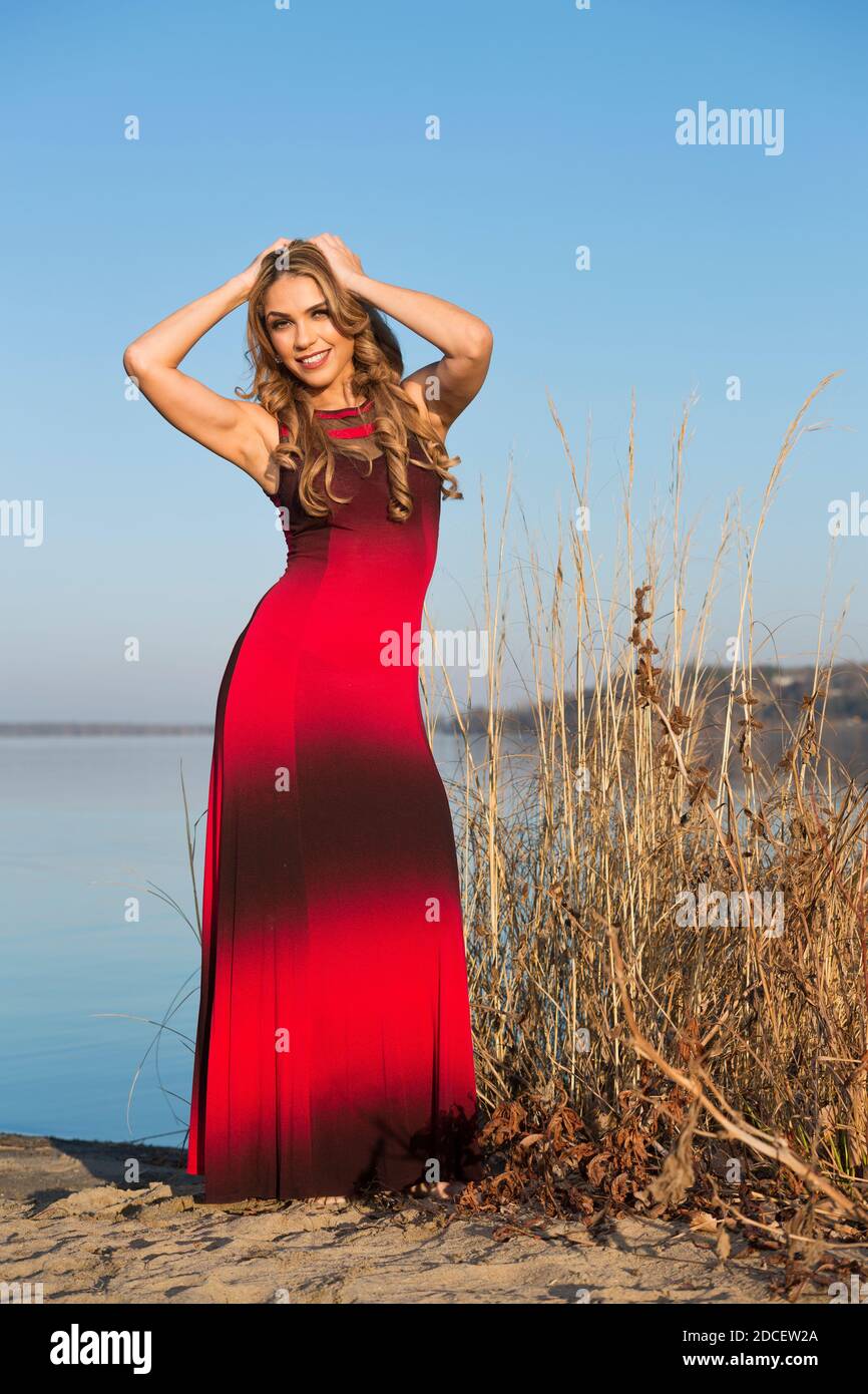 Portrait d'une femme à la plage portant un long rouge et robe noire Banque D'Images