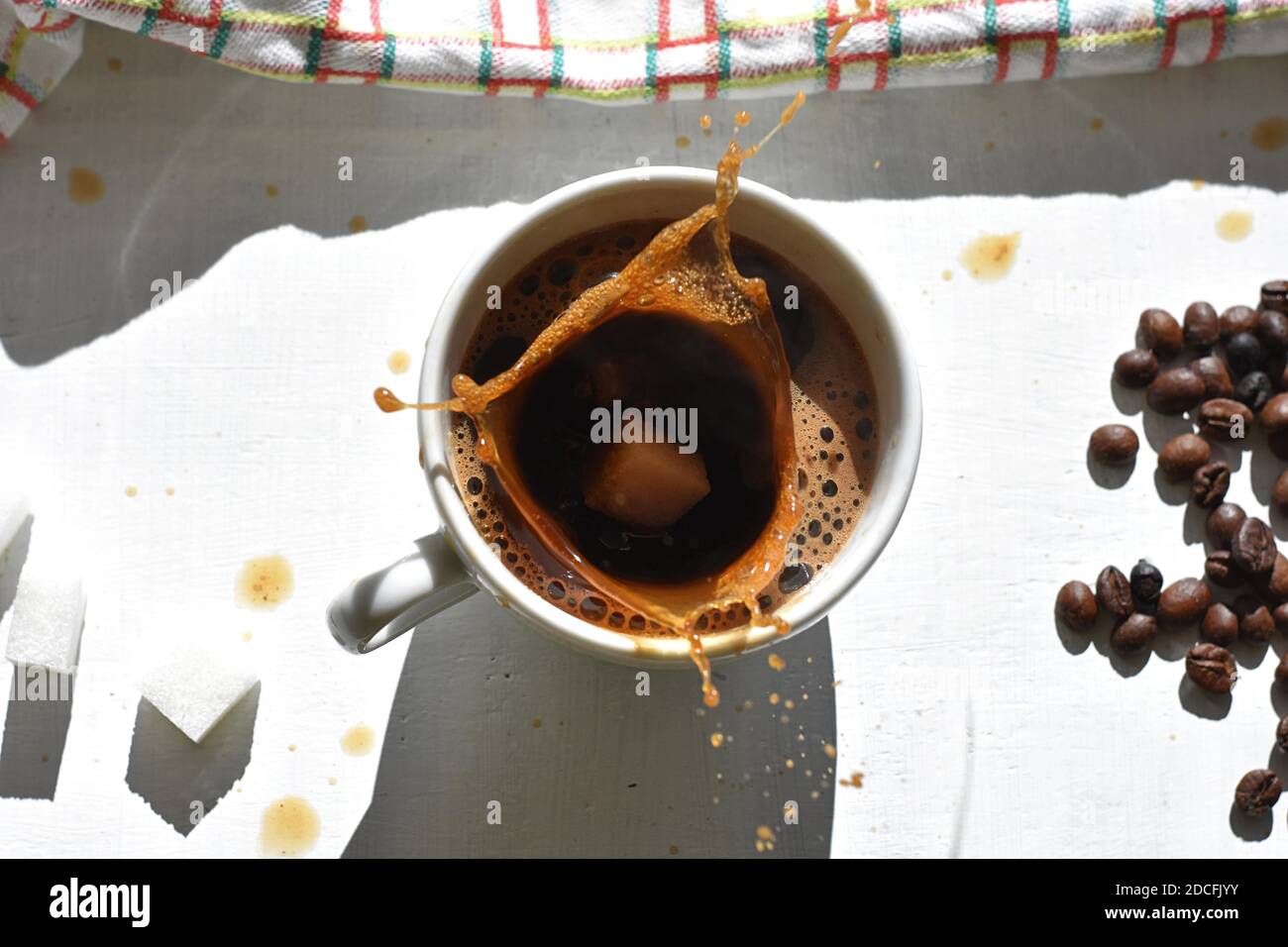 Cube de sucre tombant dans une tasse de café/UN cube de sucre déposé dans une tasse de café noir Banque D'Images