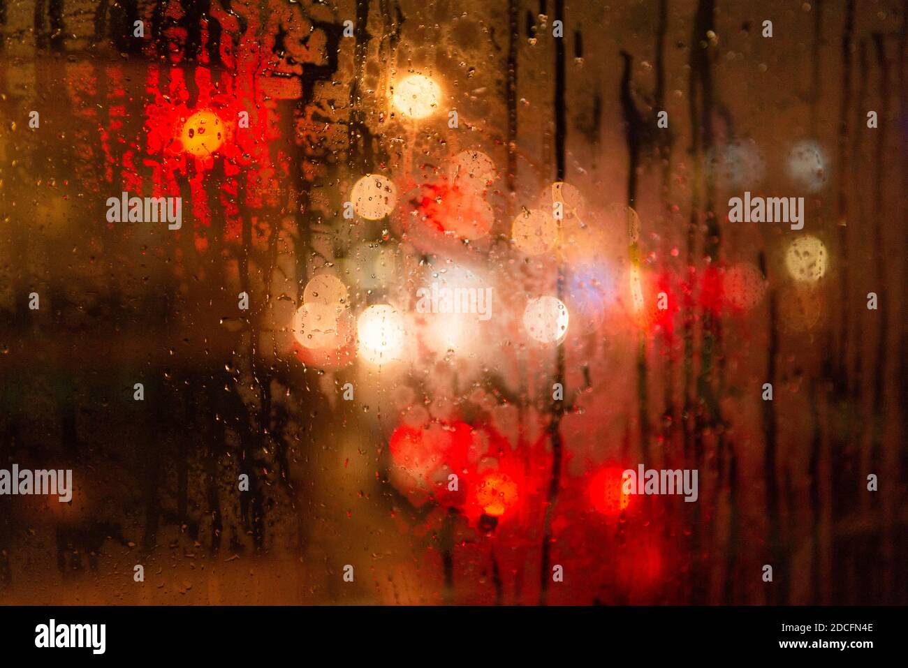 Lumières de ville floues avec effet bokeh lors d'un jour de pluie la nuit derrière un pare-brise Banque D'Images