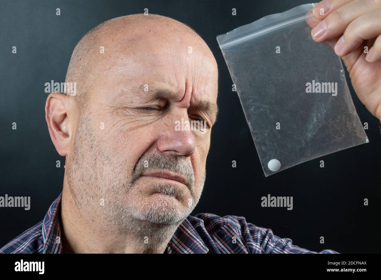 un homme en douleur avec un sac en plastique contenant un pilule Banque D'Images