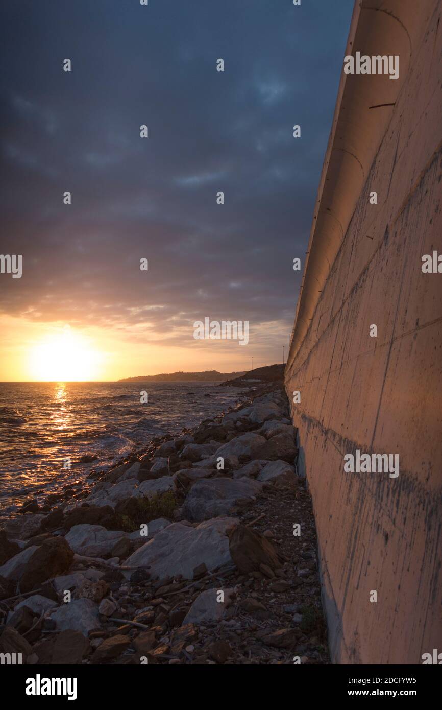 Mur en béton le long de la côte, avec l'autoroute N340 au-dessus, coucher de soleil, El Faro de Calaburras, Andalousie, Espagne. Banque D'Images