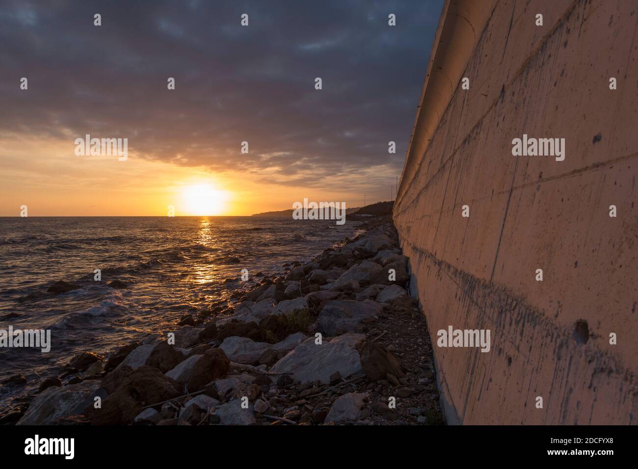 Mur en béton le long de la côte, avec l'autoroute N340 au-dessus, coucher de soleil, El Faro de Calaburras, Andalousie, Espagne. Banque D'Images
