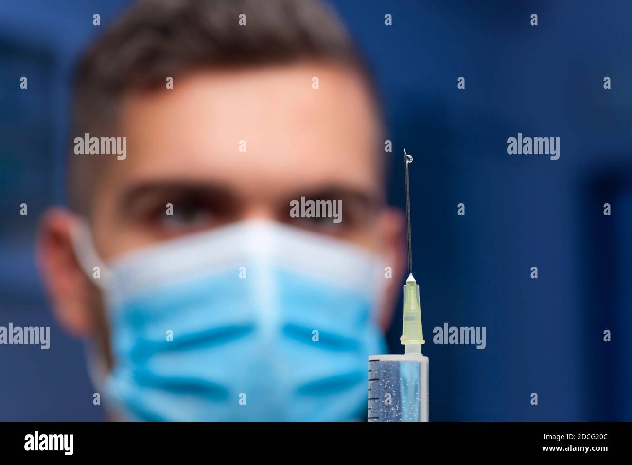 Gros plan du médecin avec un masque médical préparant une seringue pour vaccination contre le covid-19 - se concentrer sur la baisse sur le aiguille Banque D'Images