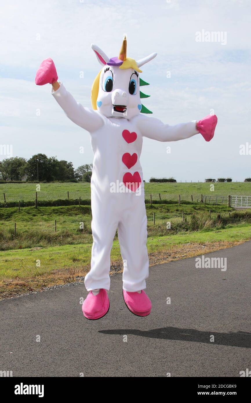 Déguisement fantaisie personnages de robe. Femme en costume de licorne rose  et blanc géant frappe sur une porte de maison Photo Stock - Alamy