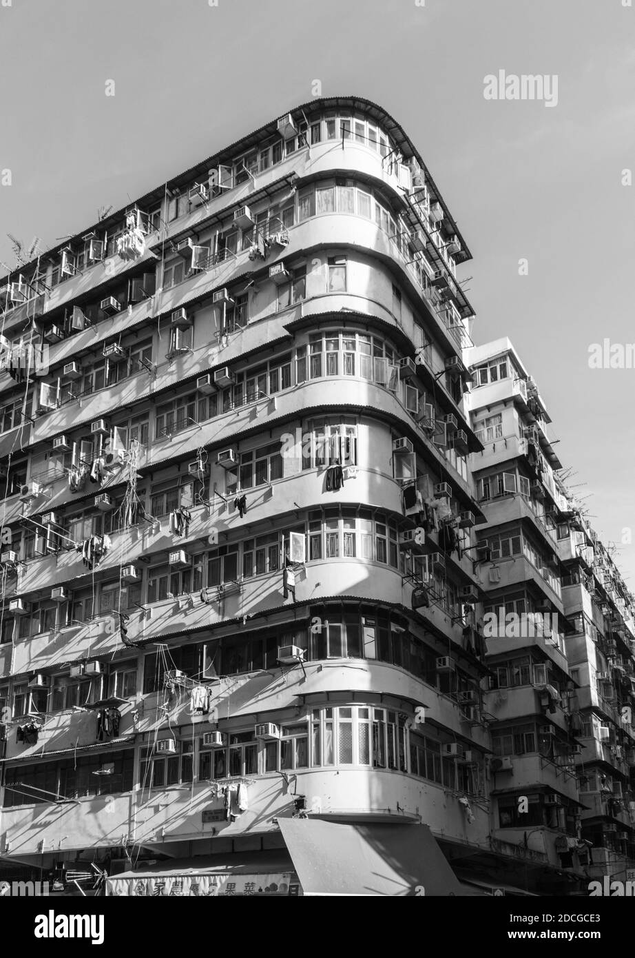 Immeuble d'appartements d'angle historique incurvé à Hong Kong. Les unités de lavage et de climatisation couvrent l'extérieur. En noir et blanc. Banque D'Images