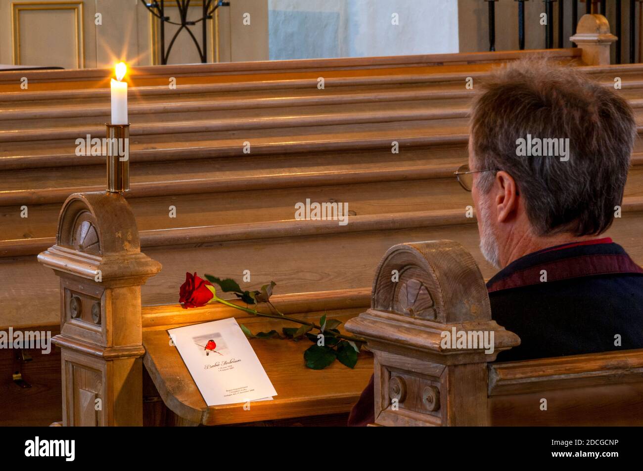 Un homme solitaire assis dans une église à un enterrement cérémonie Banque D'Images