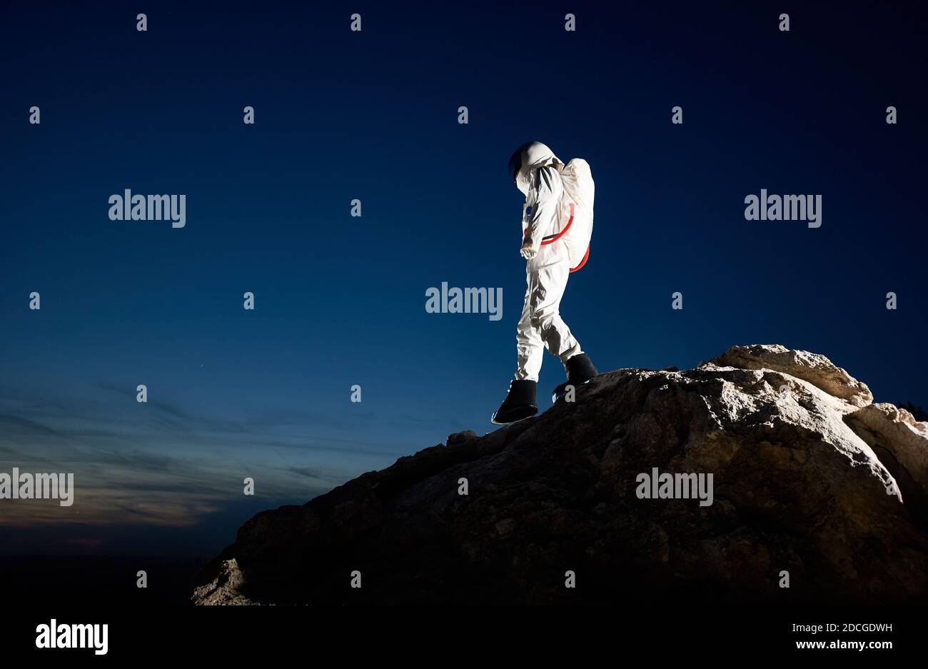 Pleine longueur de cosmonaute descendant la colline rocheuse sous un beau ciel bleu. Voyageur de l'espace portant un costume blanc avec casque. Concept d'exploration spatiale par race humaine. Banque D'Images