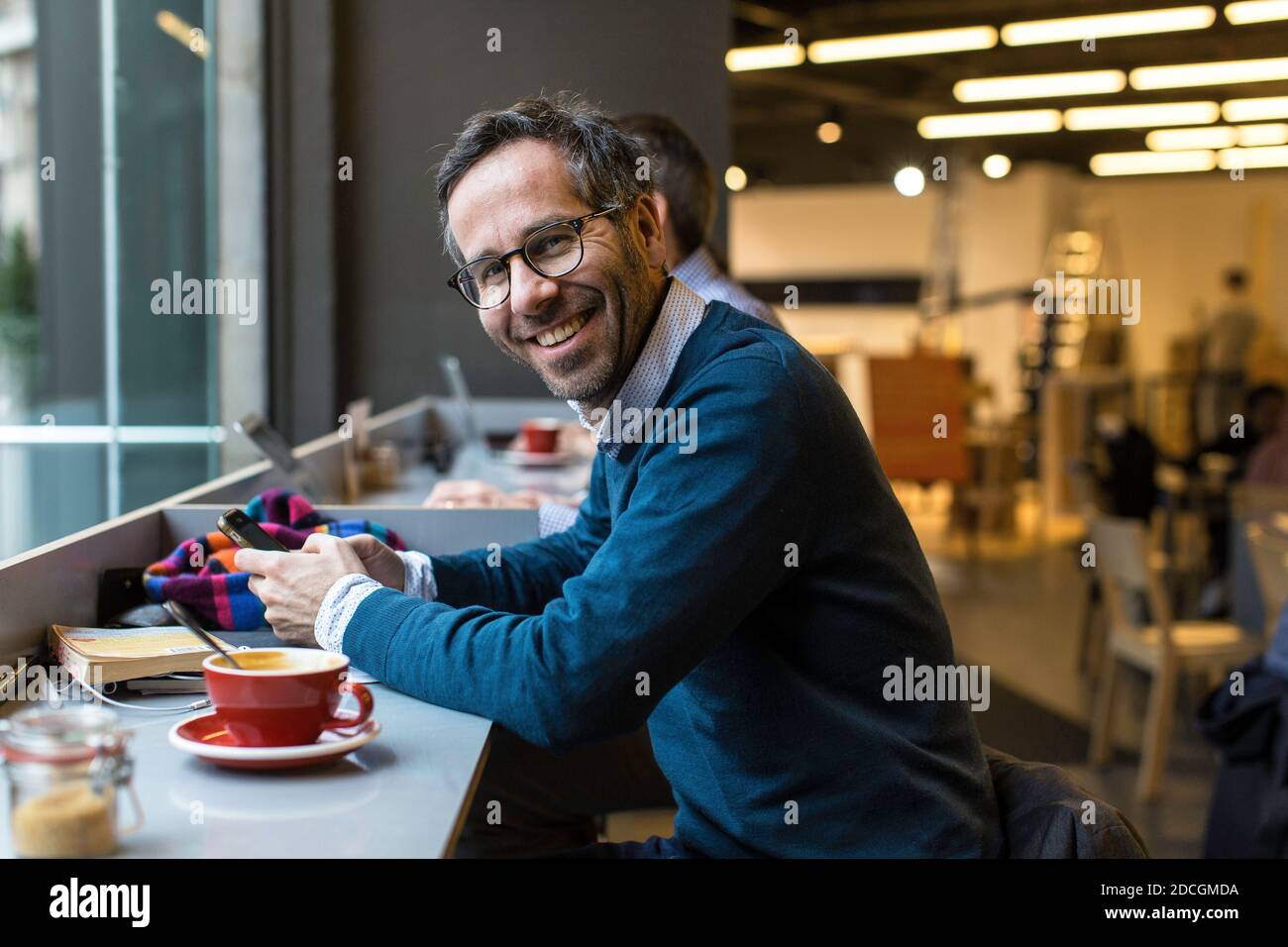 Angleterre / Londres / jeune homme de bonne apparence avec chemise bleue, cheveux foncés et la barbe est en train de lire et de répondre aux messages et les messages en ligne sur le téléphone. Banque D'Images