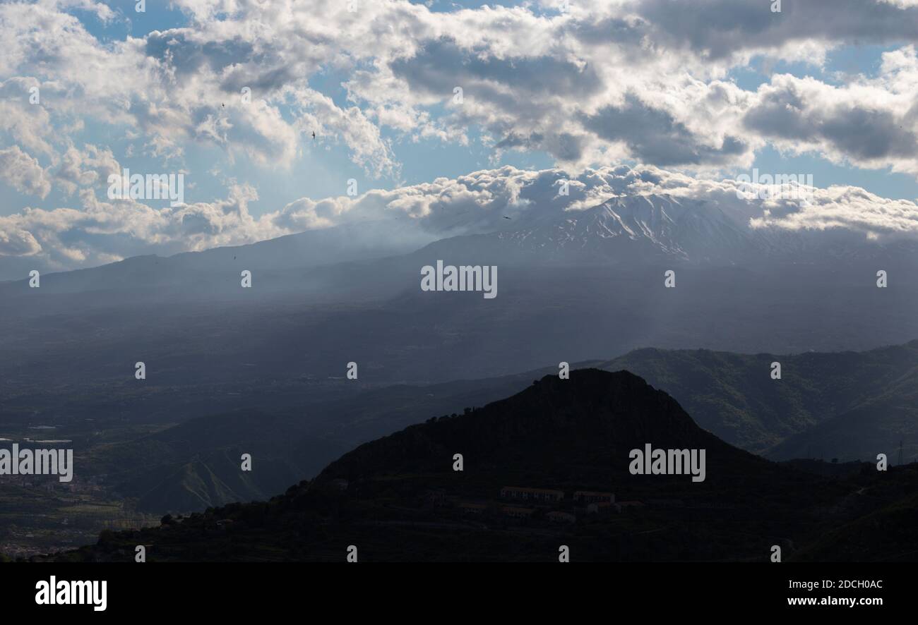 Taormina - le Mont L'Etna volcan int il nuages sur le paysage sicilien de la soirée. Banque D'Images