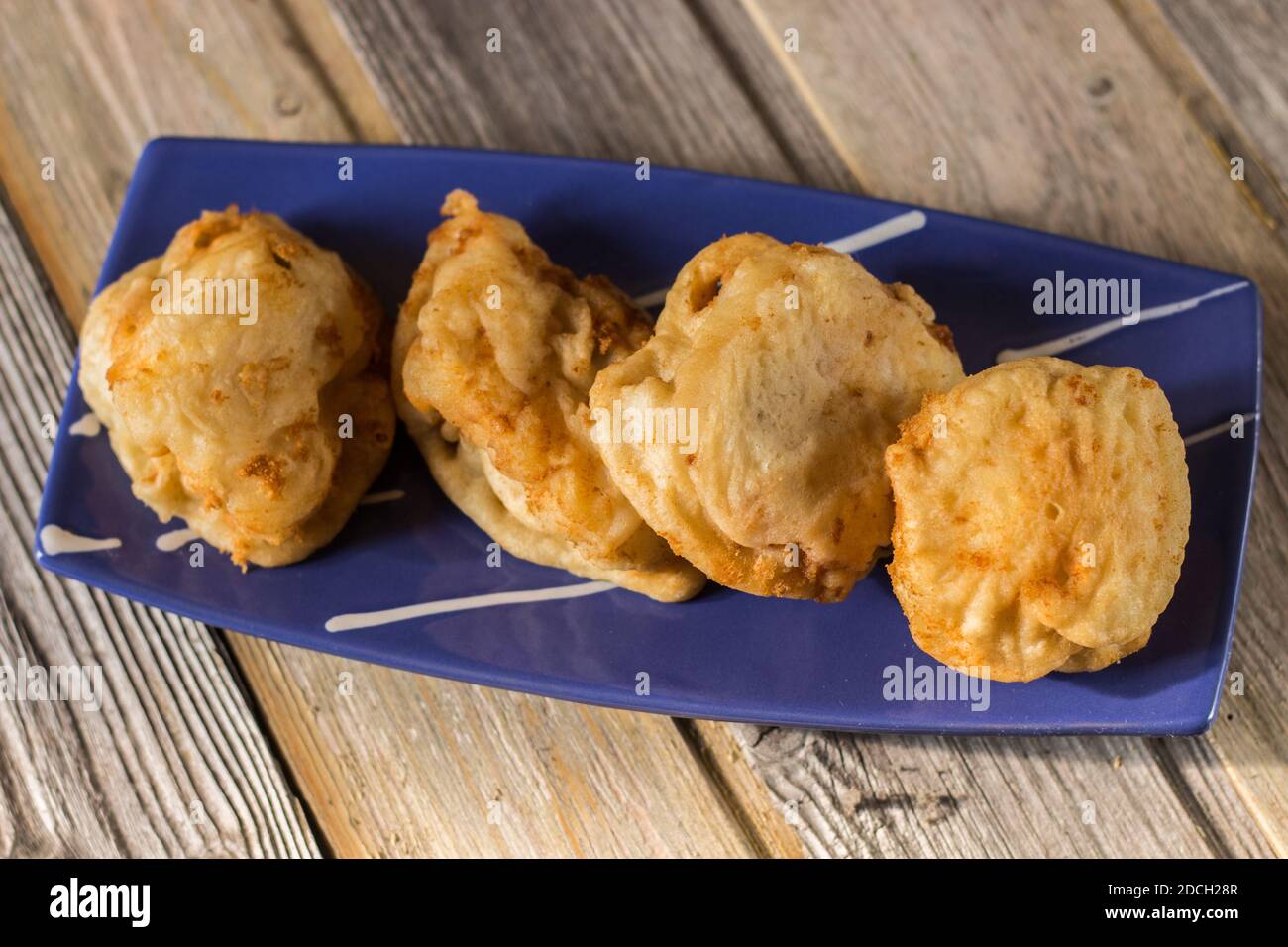 Gros plan de la morue frite servie sur une assiette bleue peinte à la main. Recette de Noël. Banque D'Images