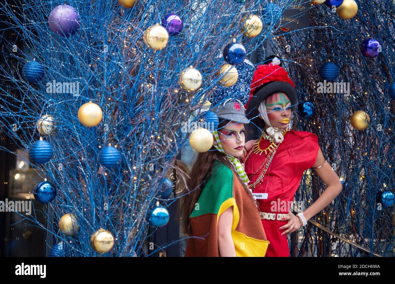 Les modèles se démarquent parmi les décorations de Noël tandis qu'ils présentent des vêtements du designer de mode Pierre Garroudi, lors d'une séance photo de mode flashmob sur Oxford Street, Londres. Banque D'Images