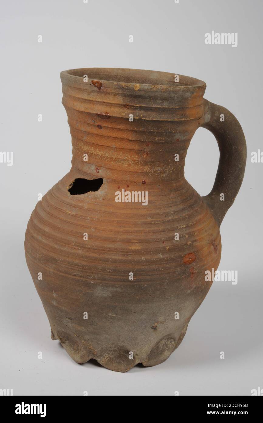 Carafe, anonyme, env. 1300, glaçure de plomb, faïence, général: 22 x 17.5 x 16cm 220 x 175 x 160mm, verseuse avec poignée en faïence rouge avec glaçure de plomb. Il a neuf pattes lobées, un corps ovoïde, un cou constrié et un col en forme d'entonnoir. Le corps est doté d'anneaux de rotation grossiers et d'une bande dentelée sur l'épaulement en relief. En bas une étiquette: Rodenburch Leiden, 1972 Banque D'Images