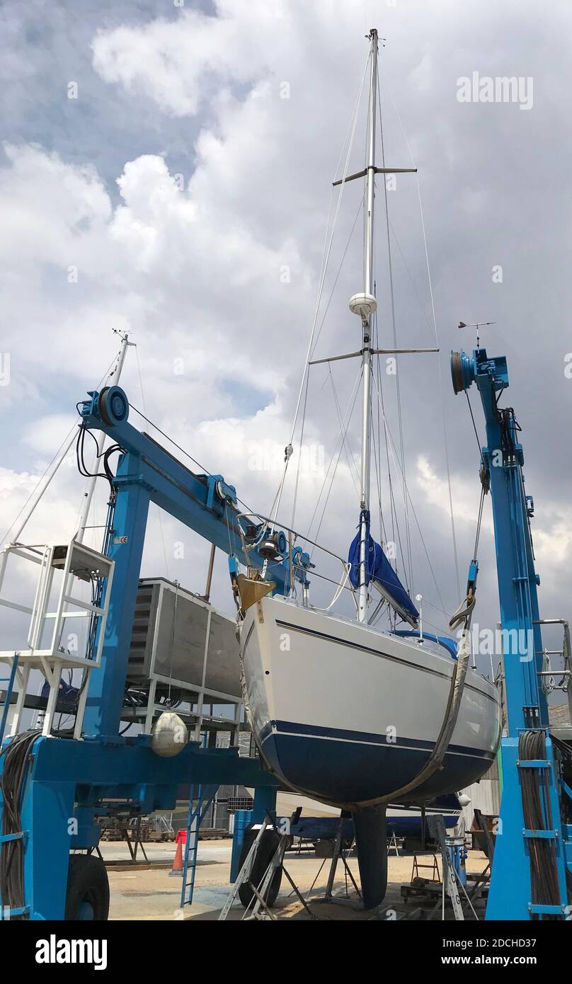 Un yacht à voile étant soulevé par une grue Banque D'Images