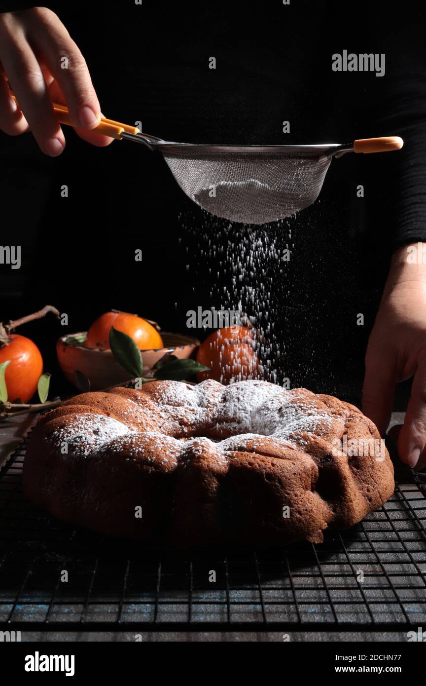 La main de femme saupoudrer le sucre glace sur un gâteau de bundt frais.  Arrière-plan sombre Photo Stock - Alamy