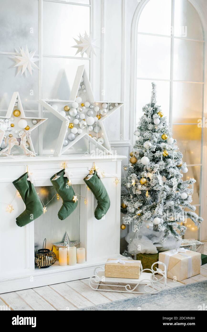 Décoration de Noël élégante dans le salon, tons or et argent. Un grand  sapin de Noël joliment décoré se trouve dans la chambre à côté du foyer  Photo Stock - Alamy