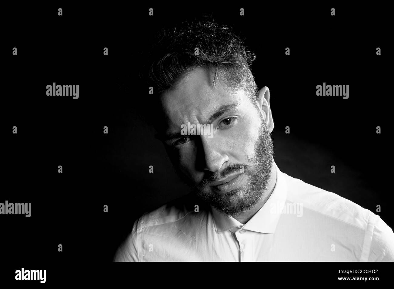 Un homme sur un fond sombre. Avec des sourcils en sillons.avec des pensées d'un avenir difficile. Banque D'Images