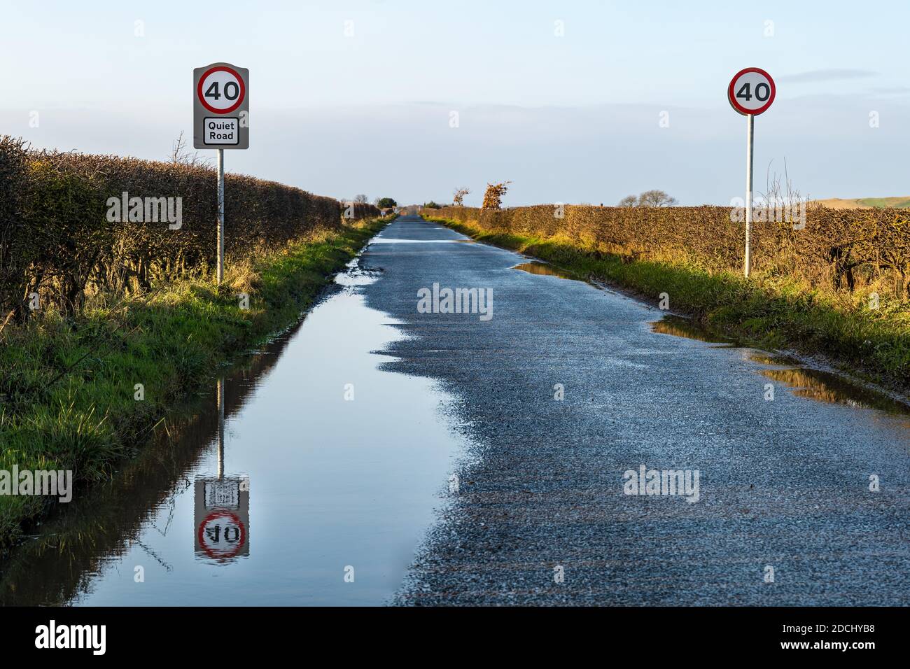 Panneau de limite de vitesse de 40 km/h sur la route de campagne nommée comme une route tranquille avec réflexion dans la flaque, East Lothian, Écosse, Royaume-Uni Banque D'Images