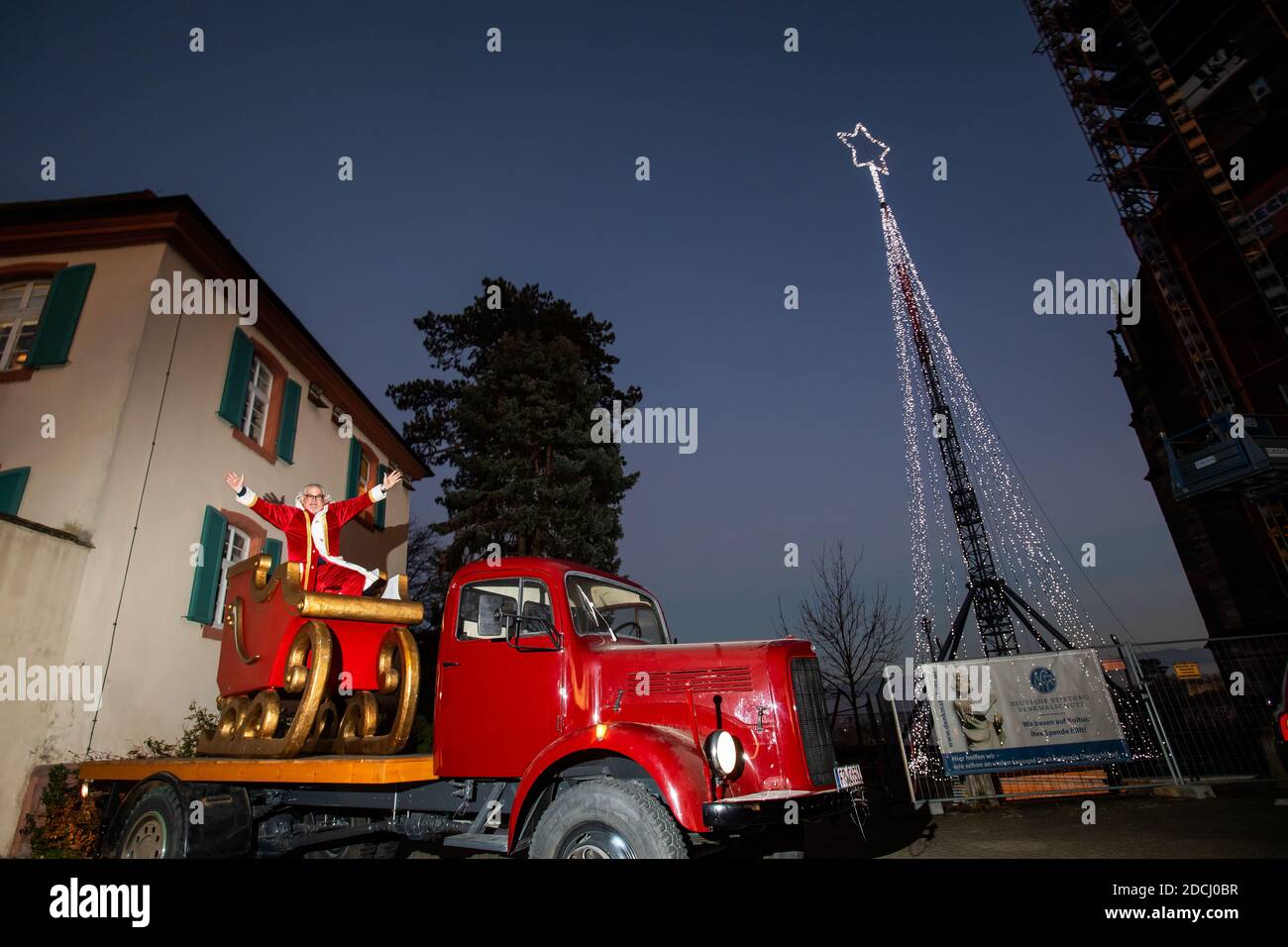 Breisach am Rhein, Allemagne. 21 novembre 2020. L'artiste de haut-fil Falko Traber s'habille comme le Père Noël dans un traîneau sur un vieux camion à côté d'un mât décoré d'une étoile et de lumières de fée. Avec ses mâts de 30 mètres de haut, Traber est normalement à un spectacle en Angleterre, mais en raison de la situation pandémique en cours, ce spectacle ne peut pas avoir lieu. Il érige donc un pôle sur la Breisacher Münsterplatz et le décorera avec une étoile brillante et des lumières de fée. Credit: Philipp von Ditfurth/dpa/Alay Live News Banque D'Images