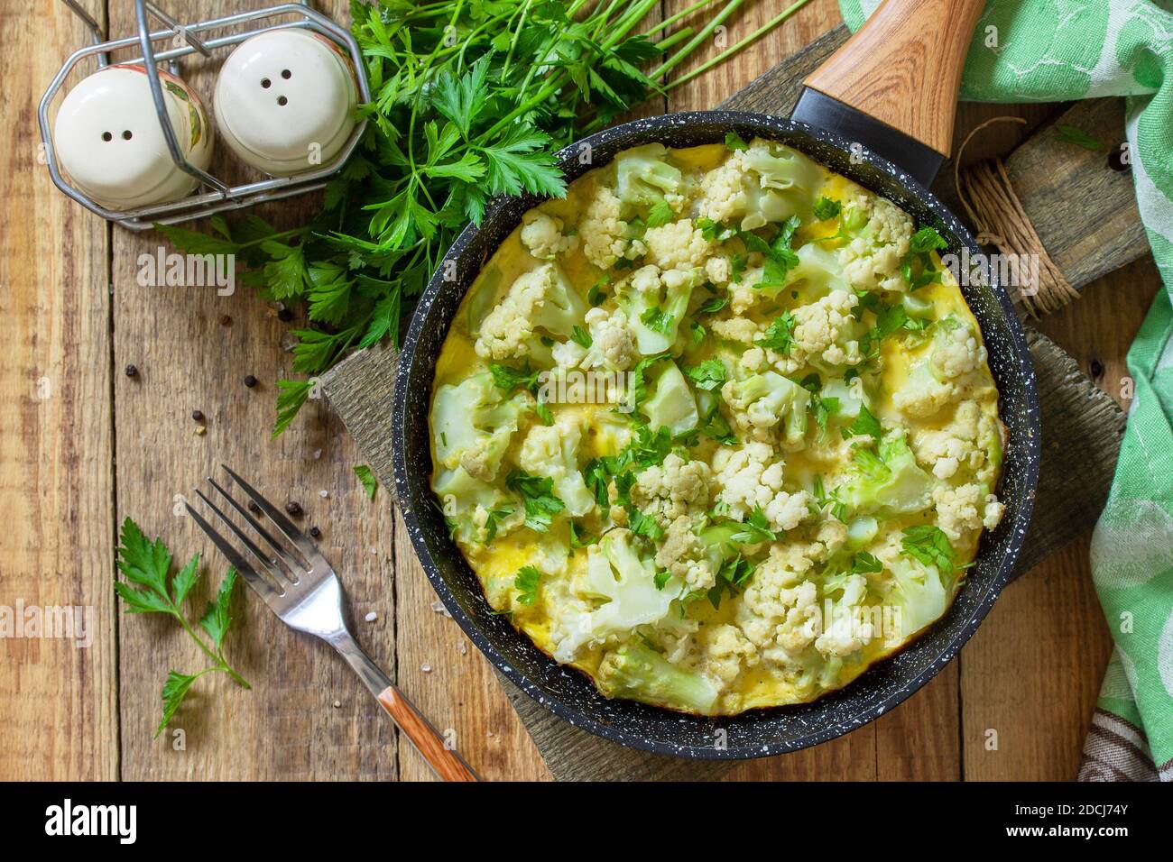 Un petit déjeuner diététique ou un déjeuner sain. Omelette aux oeufs avec chou-fleur dans une poêle en fonte sur une table rustique en bois. Vue de dessus de l'arrière-plan de la mise à plat Banque D'Images