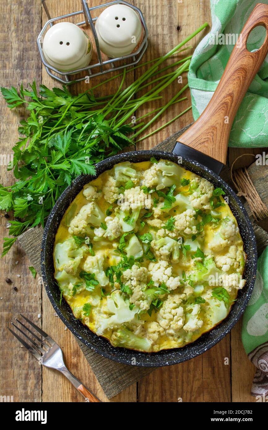 Un petit déjeuner diététique ou un déjeuner sain. Omelette aux oeufs avec chou-fleur dans une poêle en fonte sur une table rustique en bois. Vue de dessus de l'arrière-plan de la mise à plat Banque D'Images
