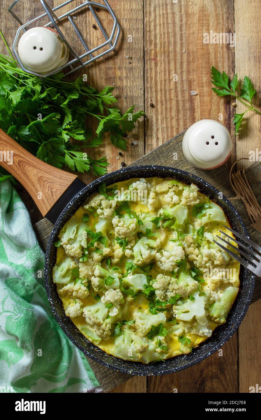 Un petit déjeuner diététique ou un déjeuner sain. Omelette aux oeufs avec chou-fleur dans une poêle en fonte sur une table rustique en bois. Vue de dessus de l'arrière-plan de la mise à plat Copier l'espace. Banque D'Images