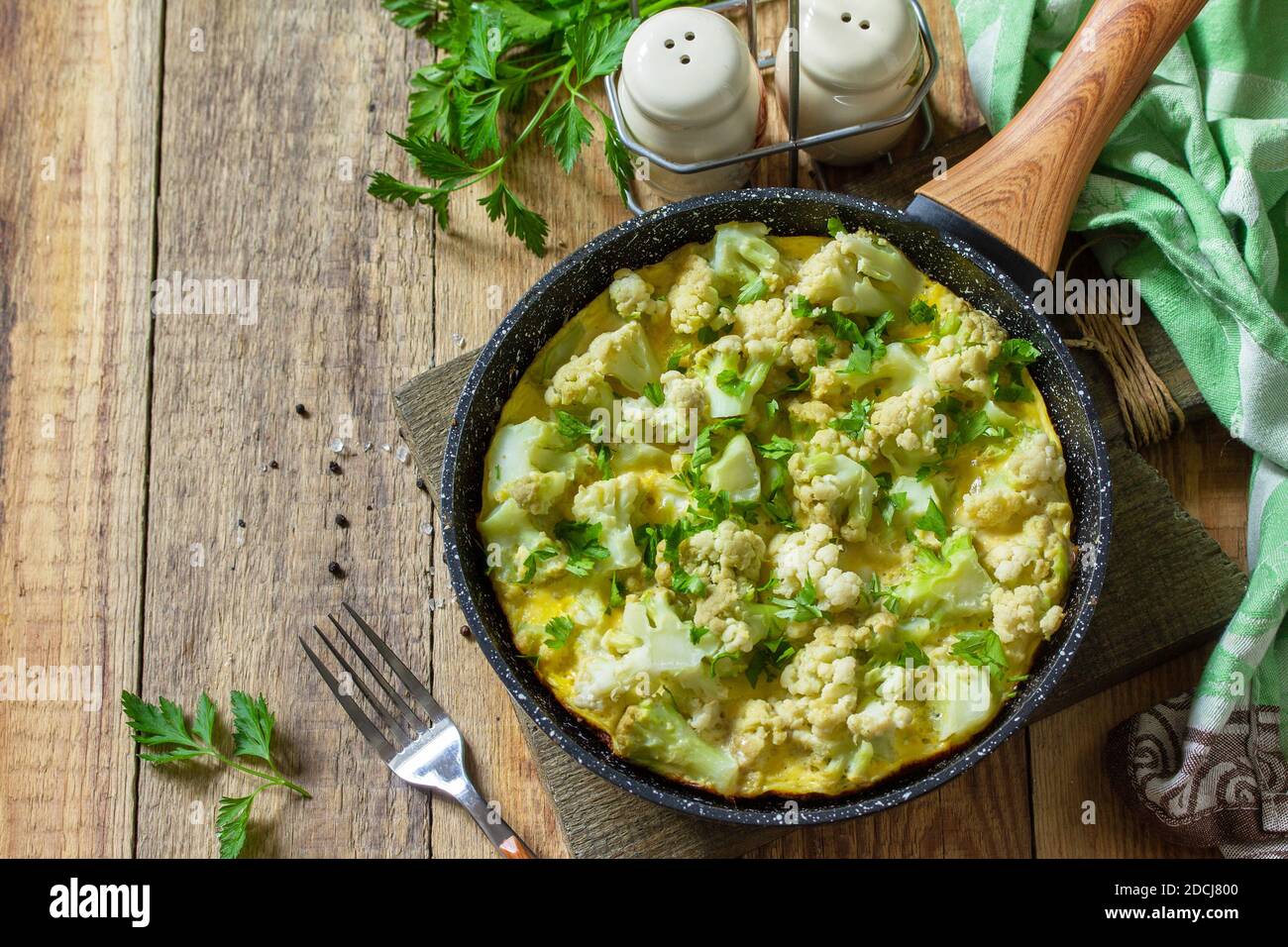 Un petit déjeuner diététique ou un déjeuner sain. Omelette aux oeufs avec chou-fleur dans une poêle en fonte sur une table rustique en bois. Copier l'espace. Banque D'Images