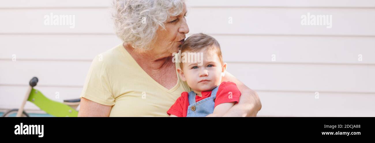 Grand-mère embrassant petit-fils garçon. Liaison de parents et communication de génération. Vieille femme avec bébé passant du temps ensemble à l'extérieur. Bannière Web il Banque D'Images