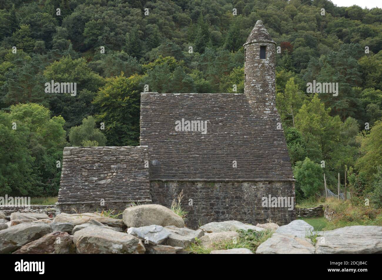 Glendalough, co. Wicklow, Irlande - août 10 2019 :Tour ronde en pierre et quelques ruines d'une colonie monastique construite à l'origine au 6ème siècle en G Banque D'Images