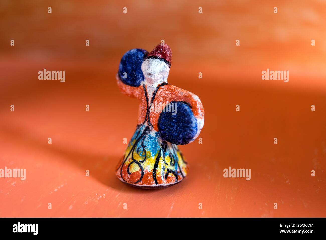 poupée en poterie colorée de dervish dansant sur fond orange pour la décoration murale. Banque D'Images