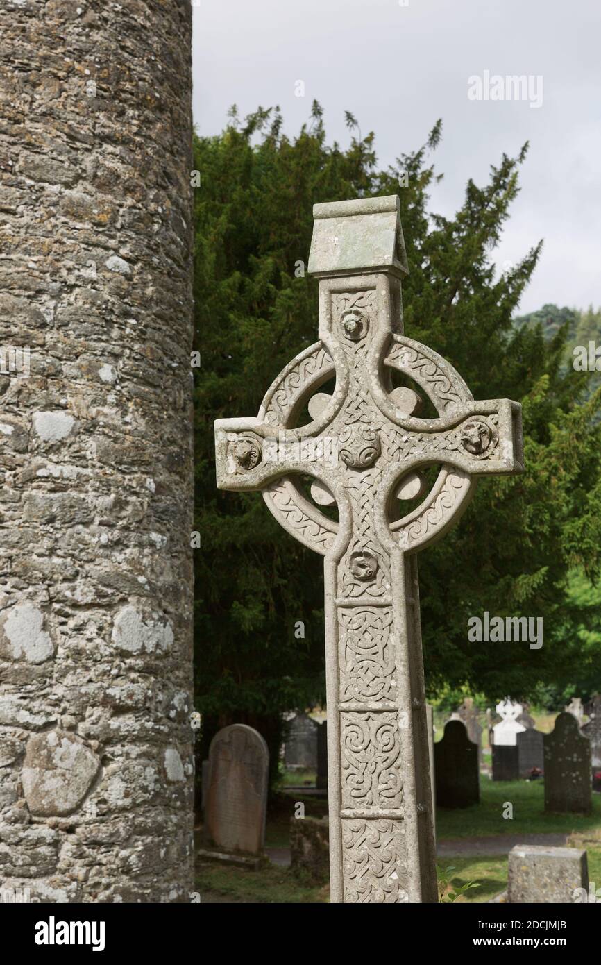 Tour ronde en pierre et quelques ruines d'une colonie monastique construite à l'origine au 6ème siècle dans la vallée de Glendalough, comté de Wicklow, Irlande. Banque D'Images