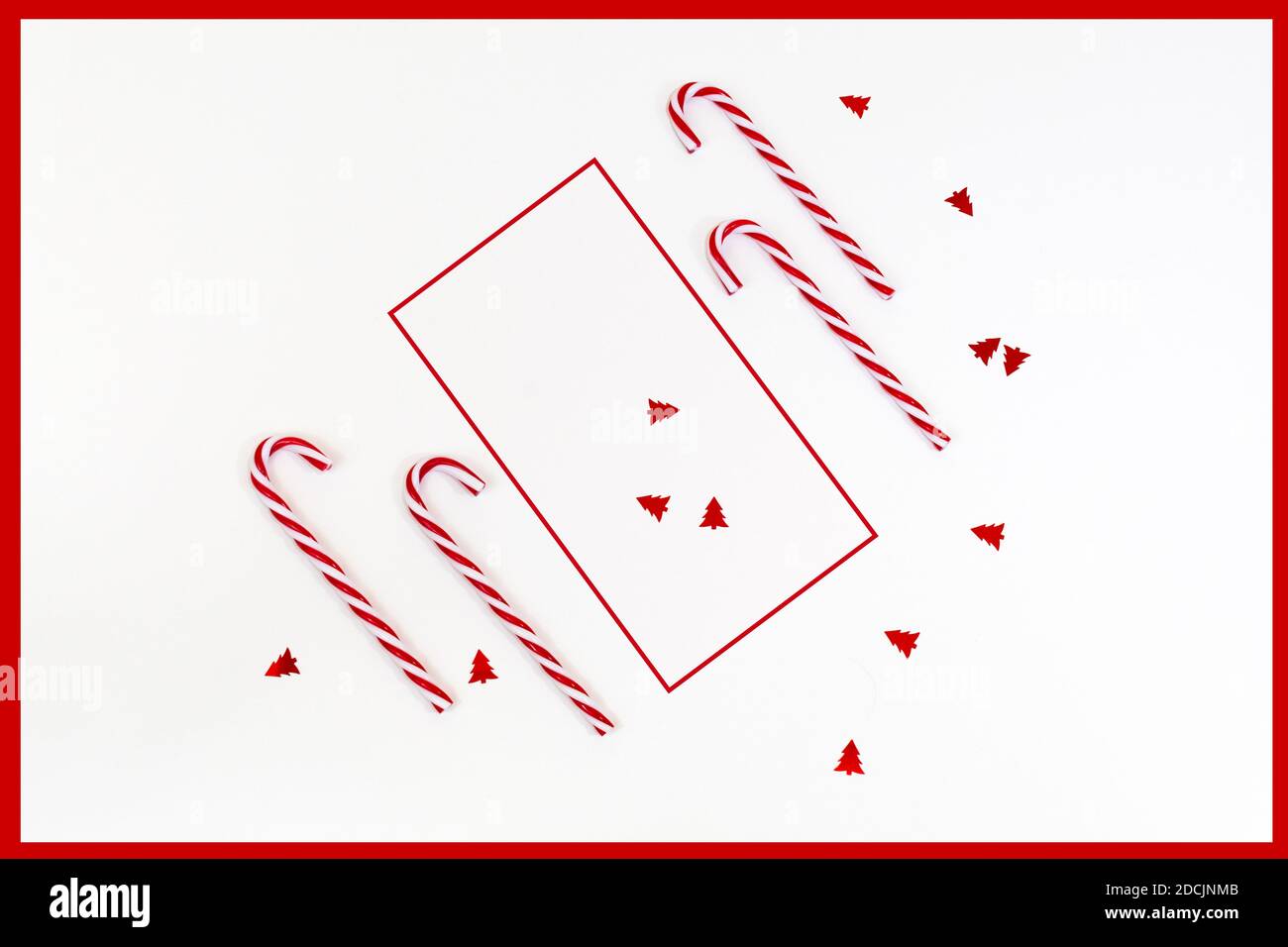 Fond de Noël moderne avec cadre rouge, Cannes de bonbons et confettis en rouge et blanc Banque D'Images