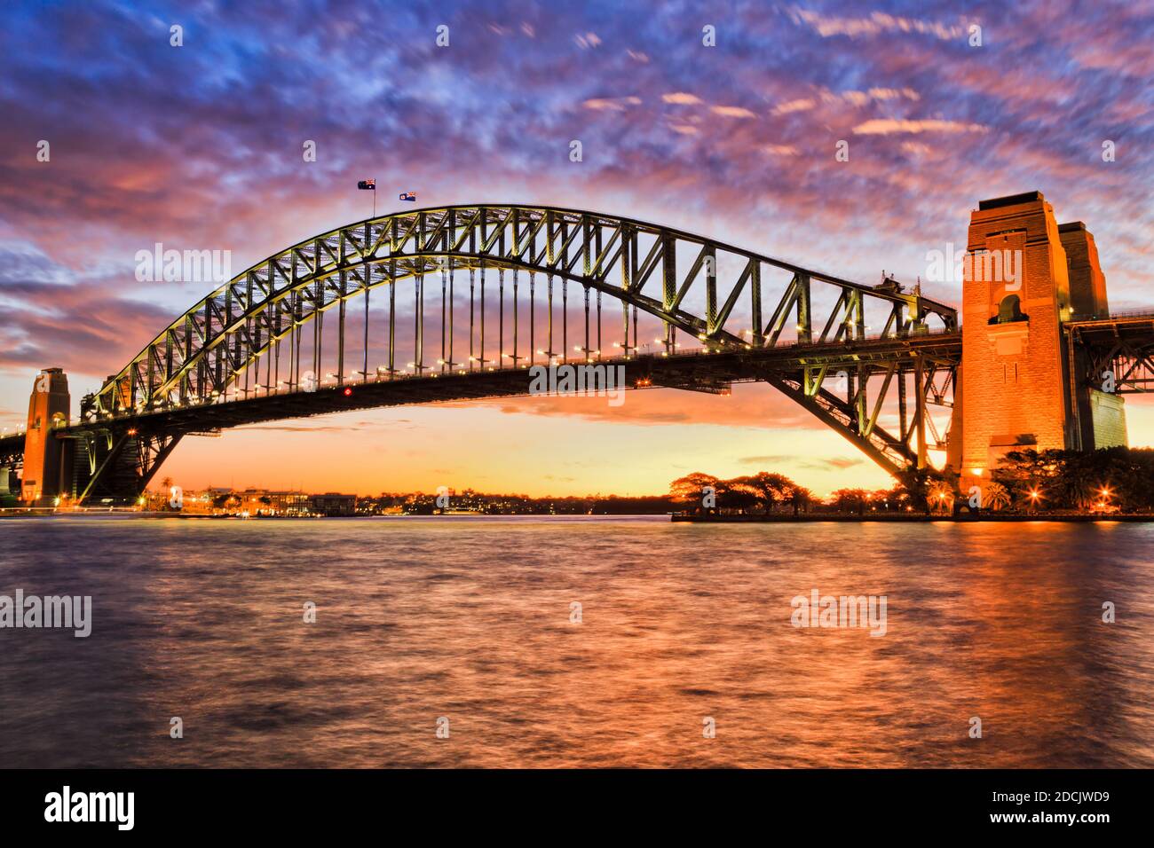 Le pont du port de Sydney traverse les eaux du port au coucher du soleil  coloré sous les nuages reflétant la lumière vive du soleil Photo Stock -  Alamy
