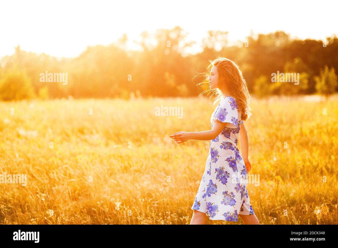 Belle tendre charmante jeune femme marchant dans le parc de fleurs en robe au coucher du soleil, style de vie sain détente en plein air scènes d'été Banque D'Images