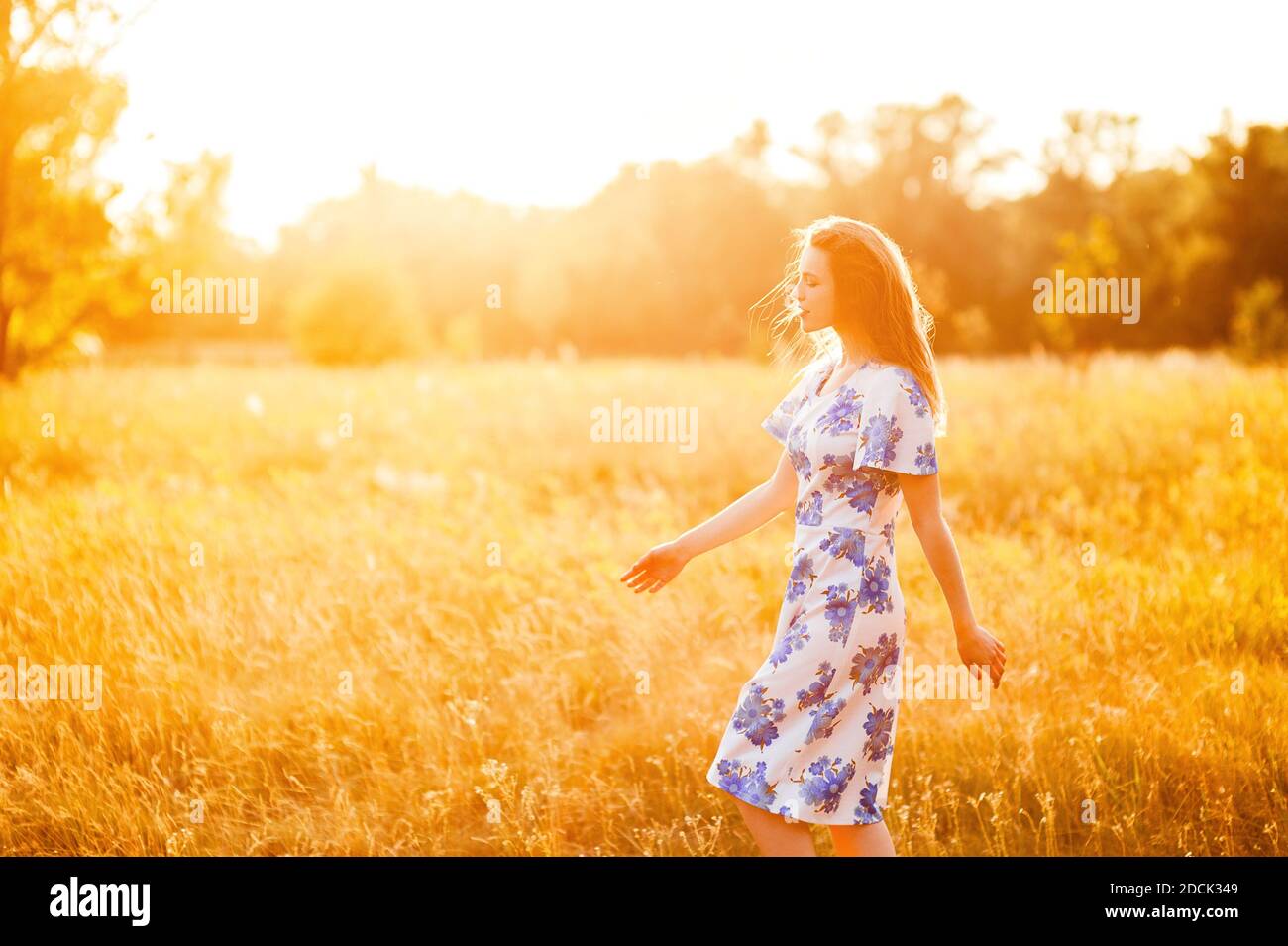 Belle tendre charmante jeune femme marchant dans le parc de fleurs en robe au coucher du soleil, style de vie sain détente en plein air scènes d'été Banque D'Images