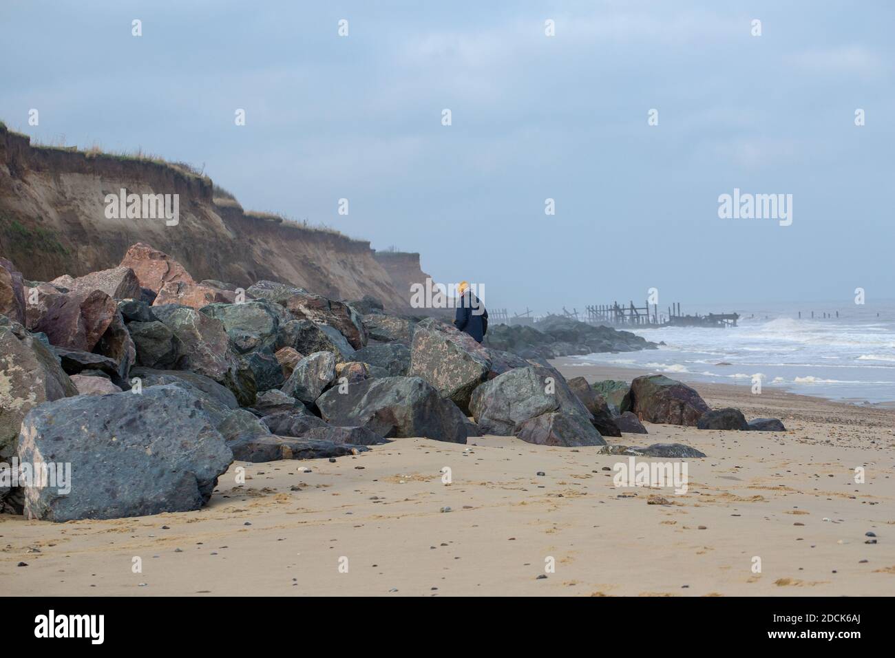 Plage de Happisburgh, Norfolk. Érosion des falaises côtières par la mer du Nord. Défenses de mer des roches de Norvège importées au premier plan, tenter de remplacer le vieux bois Banque D'Images