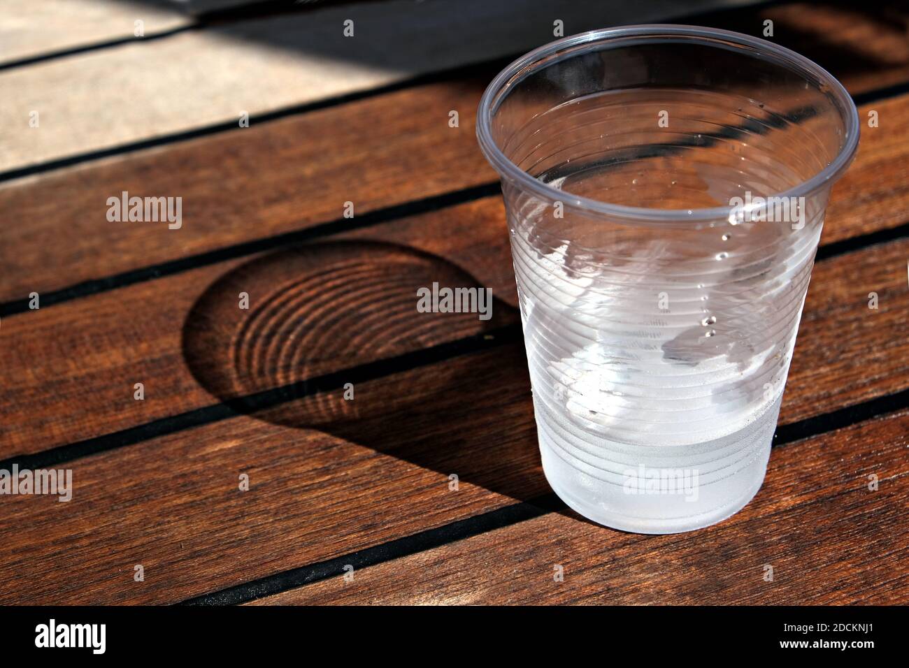 Vue rapprochée d'un verre en plastique avec de l'eau froide une table en bois Banque D'Images