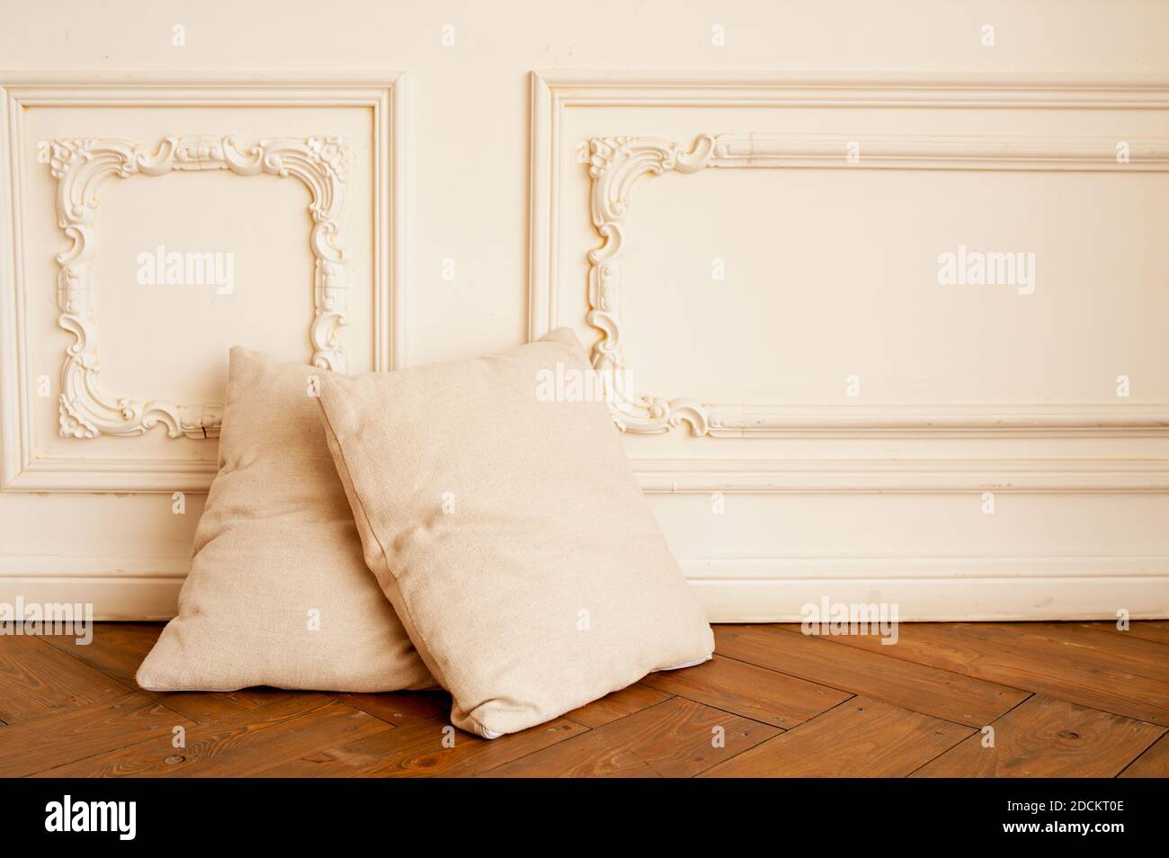 deux oreillers doux et confortables de couleur beige sur parquet et contre le mur de moulures en stuc blanc. minimalisme à l'intérieur, concentration sélective Banque D'Images